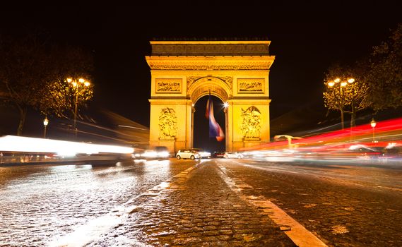 The Arc de Triomphe in Paris illuminated at night. 

