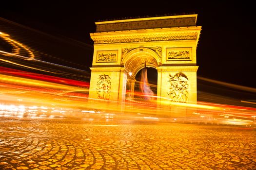 The Arc de Triomphe in Paris illuminated at night. 

