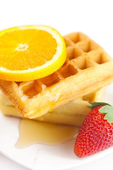 Belgian waffles,honey,orange and strawberries on a plate isolated on white