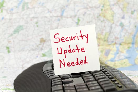 Security Update Needed note placed on black keyboard in front with map background.  Focus on technology warning phrase.  Depicts need for security from worldwide threats of virus and hacking.  Wise warning for personal computing, business, banking, government, schools, and any agency connected to today's technology. 