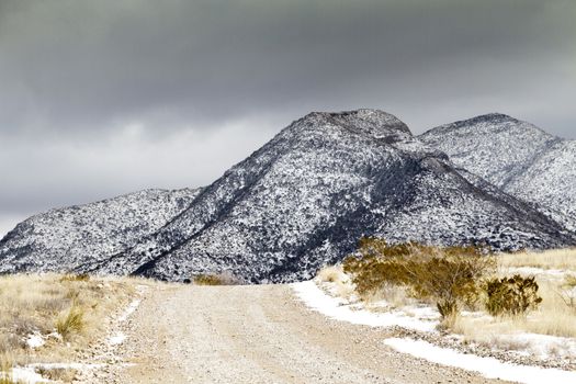 Snow touches rugged Dragoon Mountains, south of Tucson, AZ; metaphor of path and journey seen in rising road. 