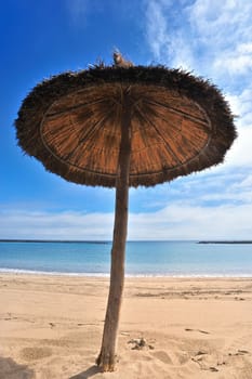 Straw parasol on the sandy tropical beach