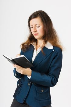 A young girl in a blue suit with a notebook writing