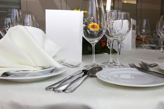 Luxury place setting with a menu card, elegant glassware and linens at a catered function or celebration