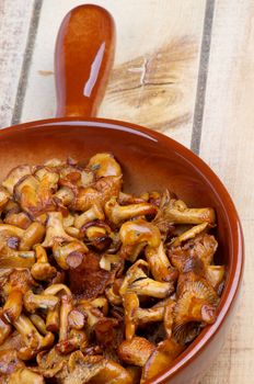 Frying Pan with Delicious Roasted Chanterelles closeup on Wooden background