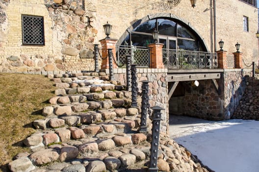 stone staircase with steel railings and light lamp leading to retro manor and snow remain in spring.