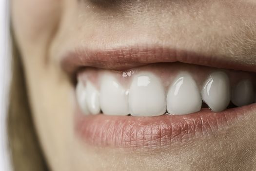 Closeup of the white teeth of a young woman with red lips