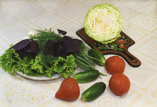 Lettuce, dill, onions on a white plate and vegetables ( tomatoes, cucumbers, cabbage).
