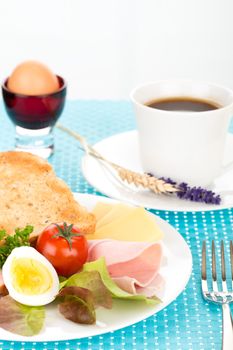 Breakfast with toast, cheese, sausage, ham, tomato, egg and cup of coffee.