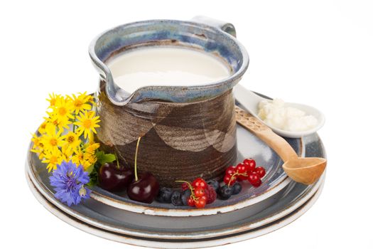 Kefir in argil jug with wooden spoon on rustic plate.