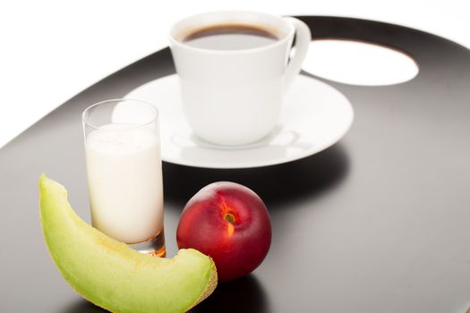 Healthy breakfast with peach, melon, glass of milk and cup of coffee.