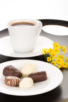 Chocolate assortment in white plate and cup of coffee.