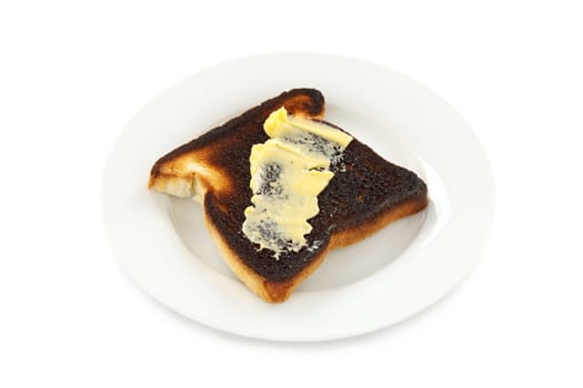 A piece of burnt toast with butter spread on it.