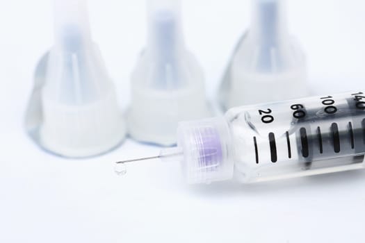 Droplets at the tip of the syringe on a white background