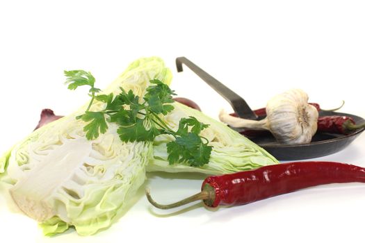 sweetheart cabbage with parsley, peppers and onions on a light background