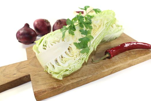 sweetheart cabbage with parsley, garlic, peppers and onions on a light background