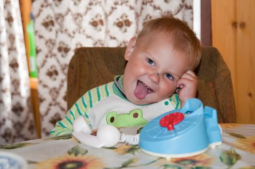 little boy sitting at a desk with a telephone