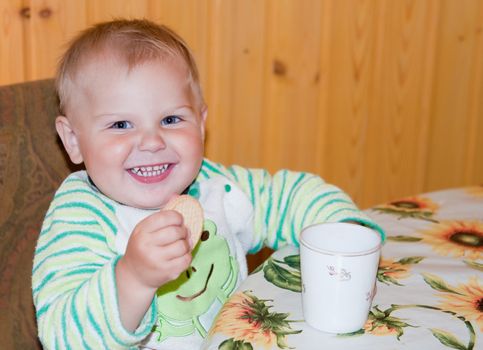 healthy baby is drinking at a table in the kitchen