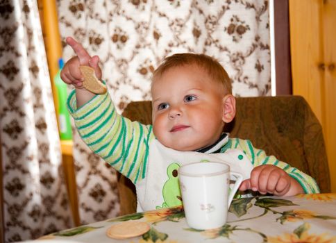 little boy is drinking at a table in the kitchen