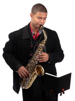 A young saxophonist plays by reading from a book on a stand.