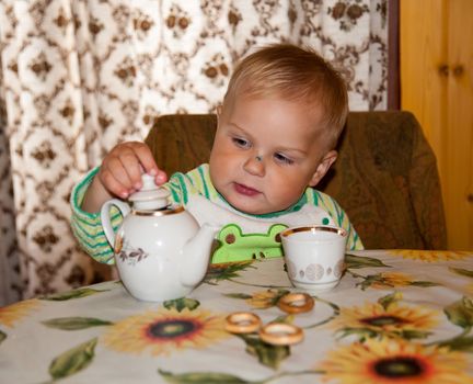 little boy is drinking at a table in the kitchen