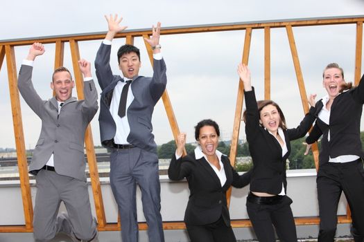 Successful multiethnic business team cheering and rejoicing leaping in the air with their arms raised