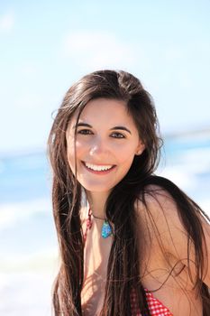Portrait of a beautiful woman with long brunette hair and a lovely friendly smile at the beach