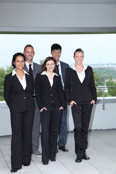 Successful professional business team of dedicated multiethnic young people posing in front of their office building in smart stylish suits