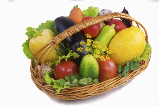 Wicker basket with a variety of vegetables , salad, fruit. Presents on a white background.