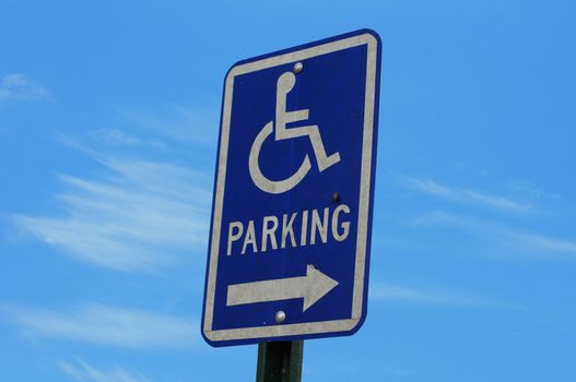 A bright blue handicapped parking sign against blue sky