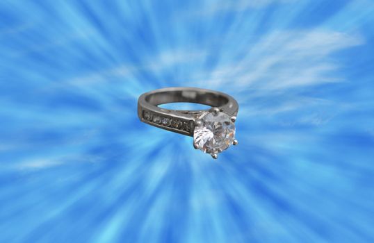 a diamond solitaire engagement ring in the middle of a sunburst or sun-rays and a blue sky