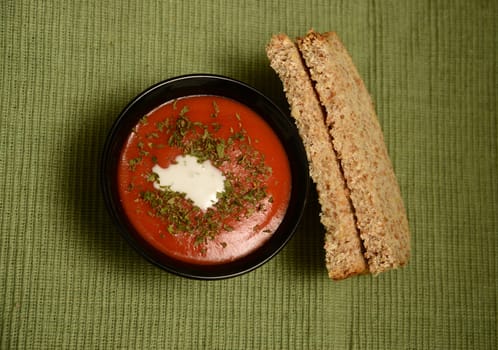 warm bowl of tomato soup with cream and whole grain bread