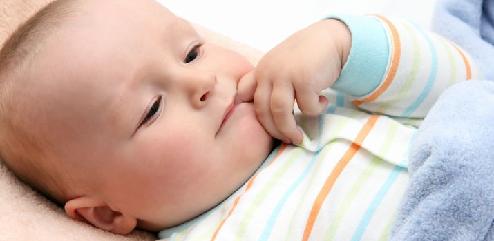 baby in bed with  finger in mouth