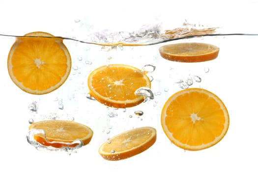 Sliced Oranges Falling Into Splashing Clear Water