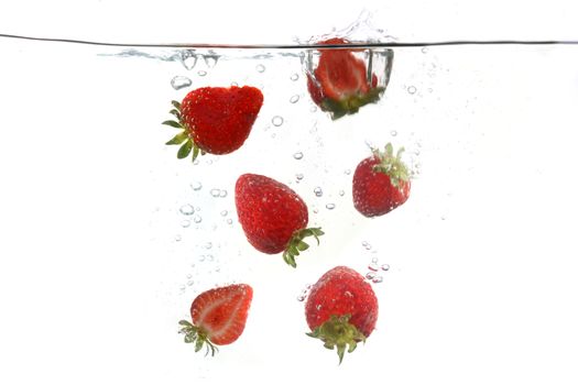 Sliced Strawberries Falling Into Splashing Clear Water