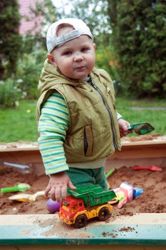 working boy playing in a sandbox with a car