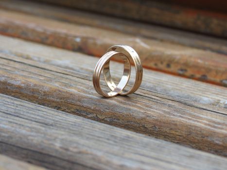    On a wooden board are two wedding rings placed on a smaller more                            