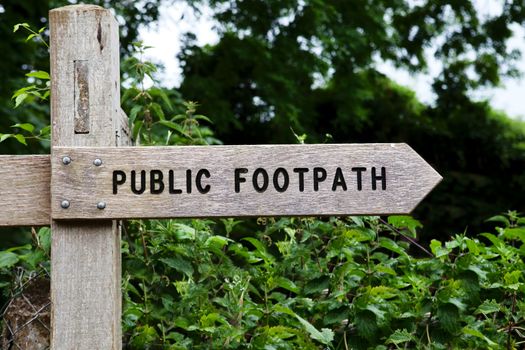 Public footpath wooden sign, shallow depth of field used to blur the background.