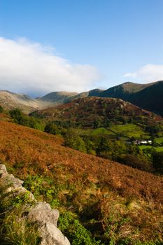 View over hills and valleys in the lake district, cumbria, national park, small stone wall. Taken in Autumn. Lovely clear day with blue sky and white fluffy clouds