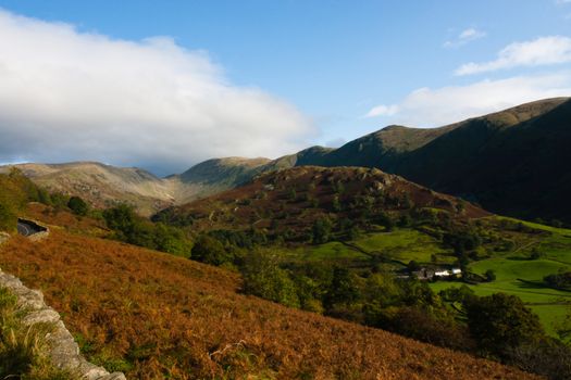 View over hills and valleys in the lake district, cumbria, national park, small stone wall. Taken in Autumn. Lovely clear day with blue sky and white fluffy clouds