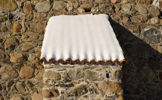 Retro fortification castle wall made of stone and small clay tile roof covered with snow in winter.