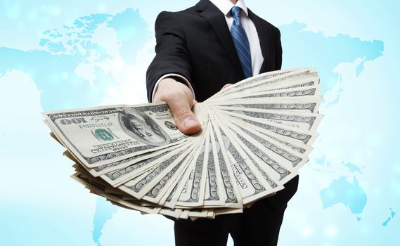 Business Man Displaying a Spread of Cash over blue world map background