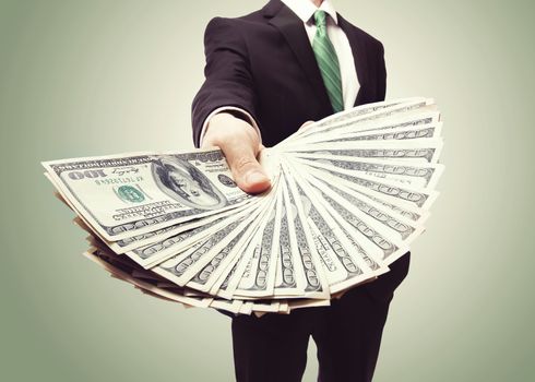 Business Man Displaying a Spread of Cash over a green vintage background