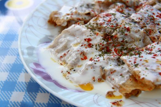 turkish manti manlama on plate with red pepper and mint on it