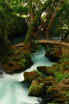 bridge on waterfall with tree and tourquoise stream