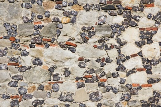 Multicoloured stone background of a building exterior facade with different sizes, colours and textures of stones.