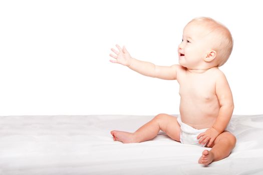 Cute adorable infant baby reaching out with hand asking for something while sitting, on white.