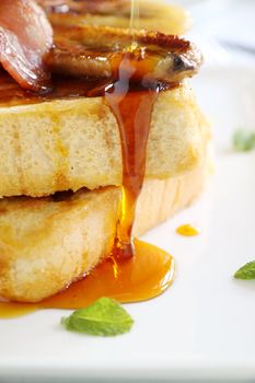 Maple syrup dripping down caramelized banana and french toast.