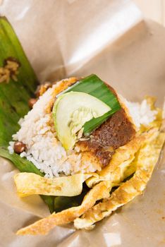 A pack of nasi lemak (Malaysia National Dish) on dining table ready to eat.