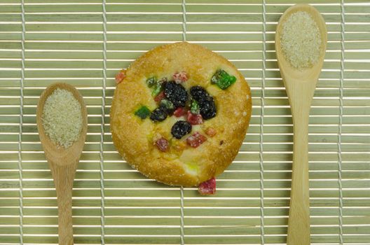 top view of  bread with raisin and  dried fruits and two spoon of sugar on wooden background 